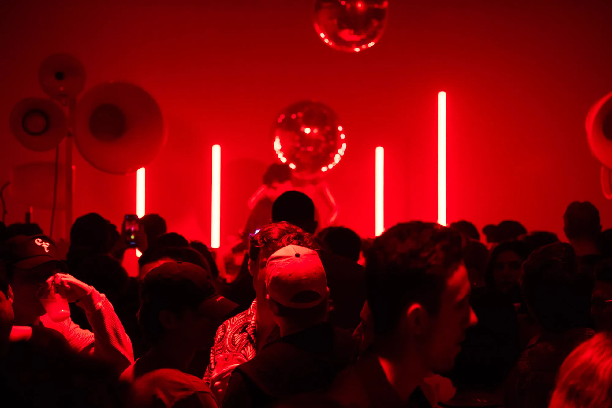 Packed dance floor in a red-lit room with white Void Acoustics speakers