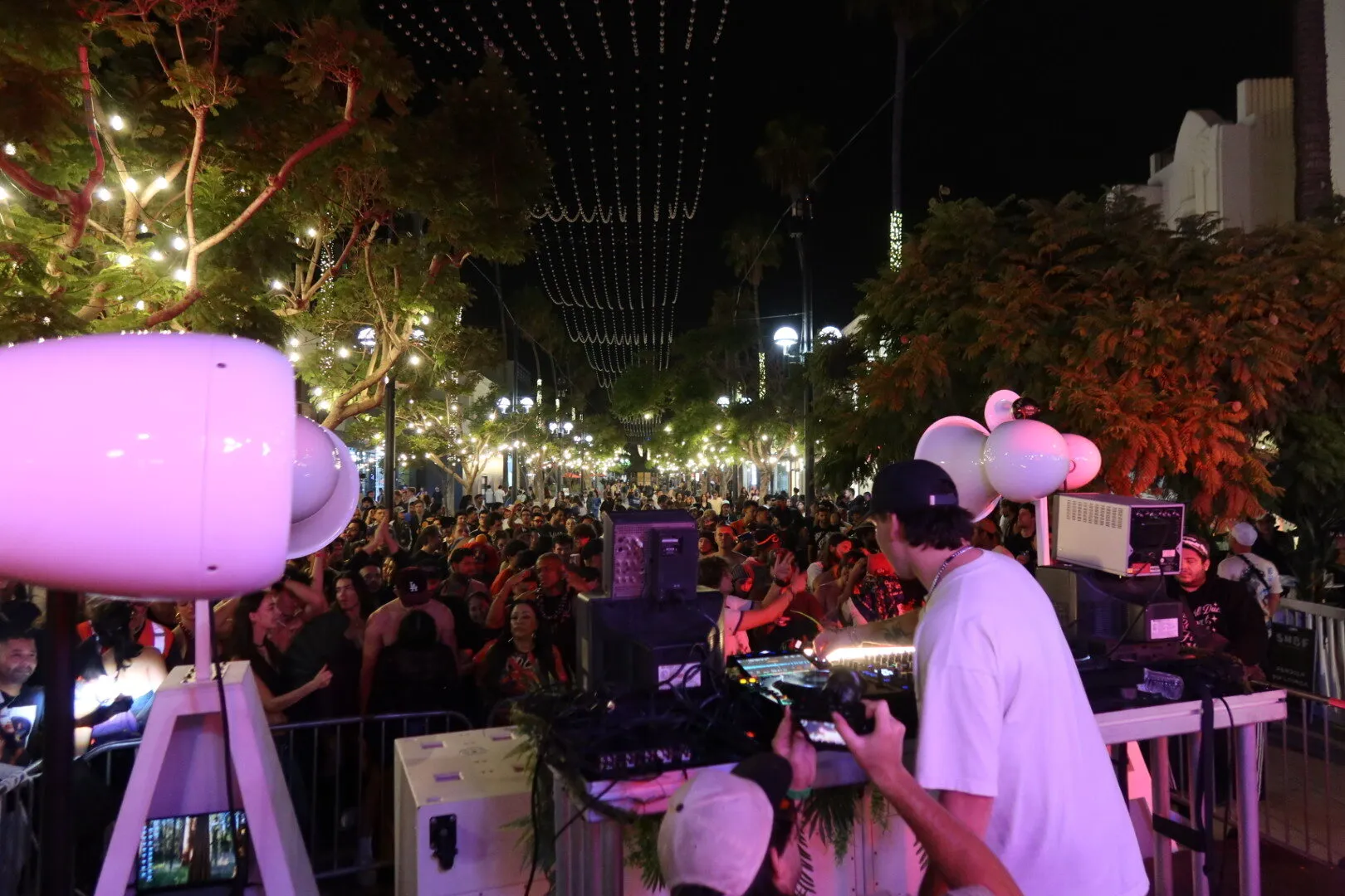 View from the DJ booth past a white Void speaker over the festival crowd