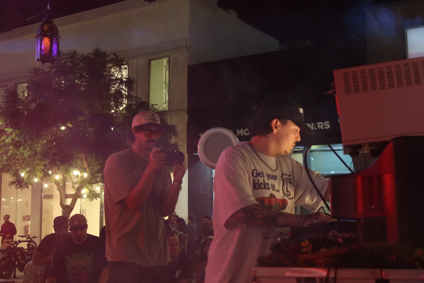 DJ playing in the Good Society booth with a photographer beside him